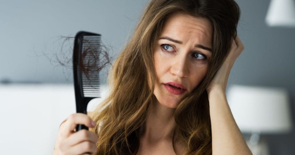 ragazza guarda i capelli persi sulla spazzola