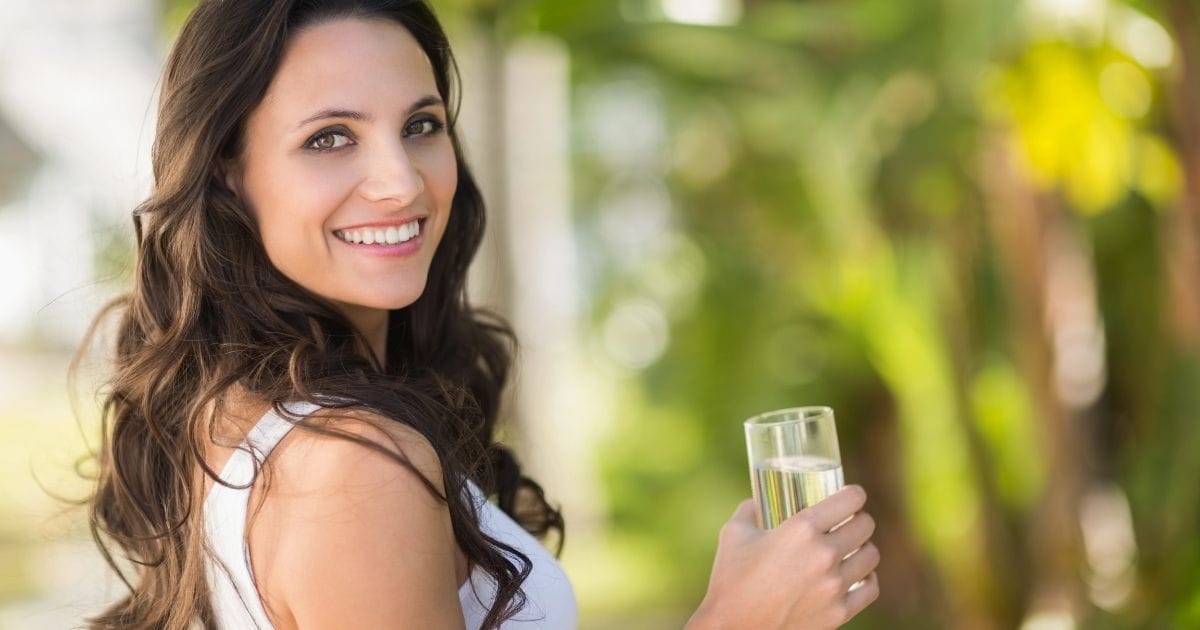 donna con un bicchiere di acqua in mano