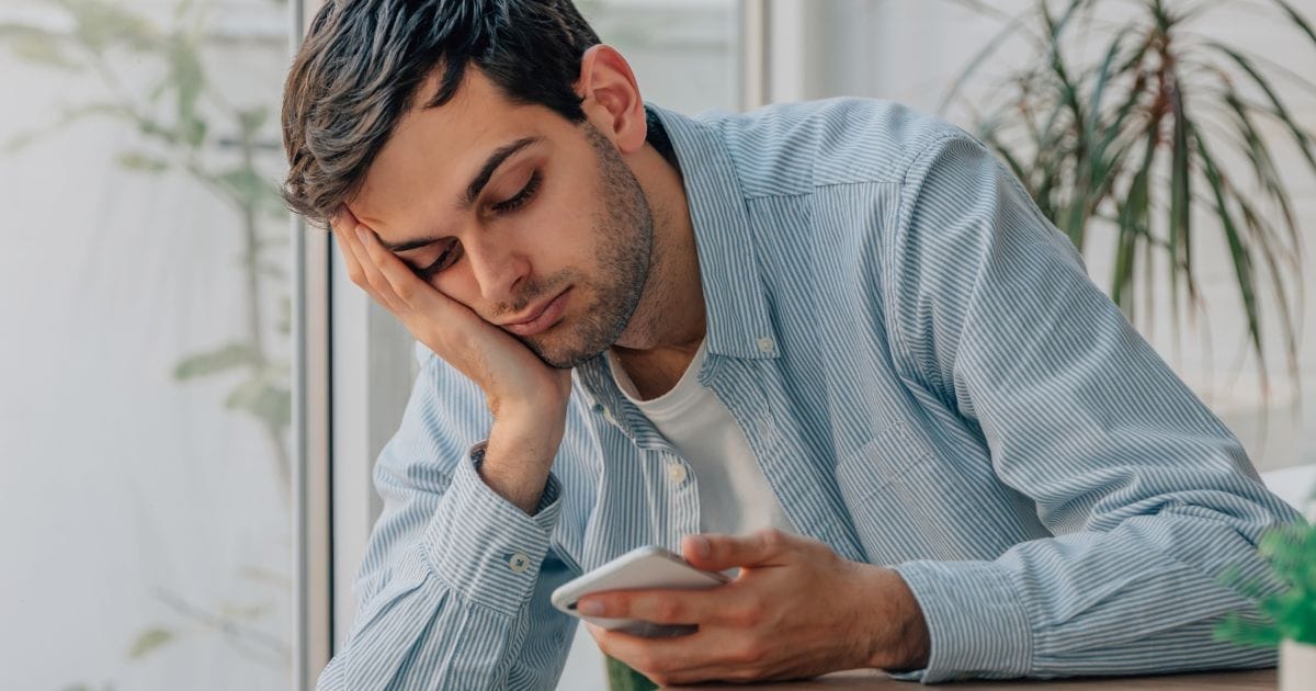 ragazzo guarda il cellulare, è molto stanco