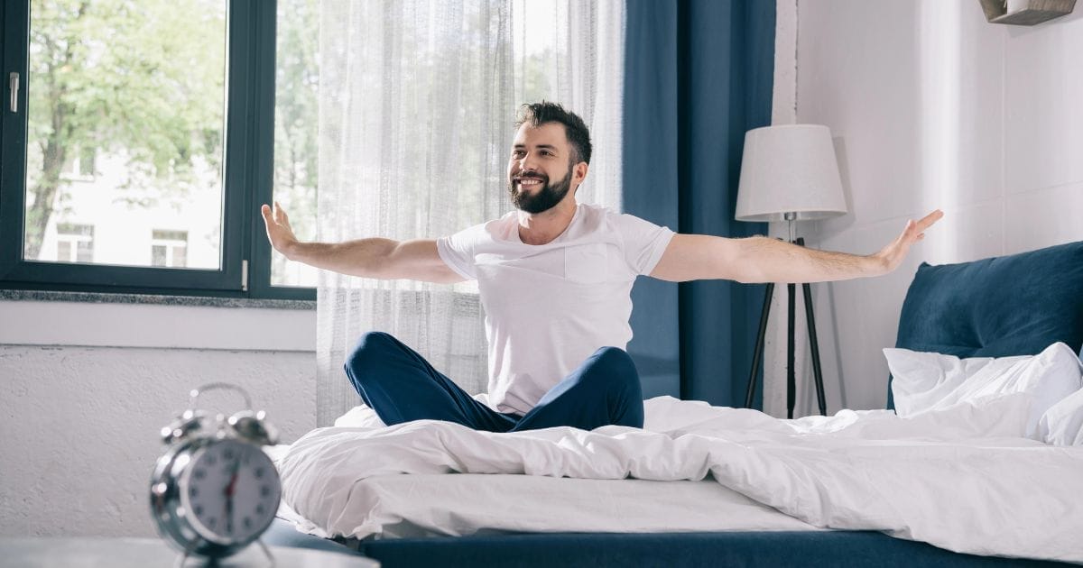 uomo si sveglia riposato sul letto al mattino perché ha capito come dormire meglio